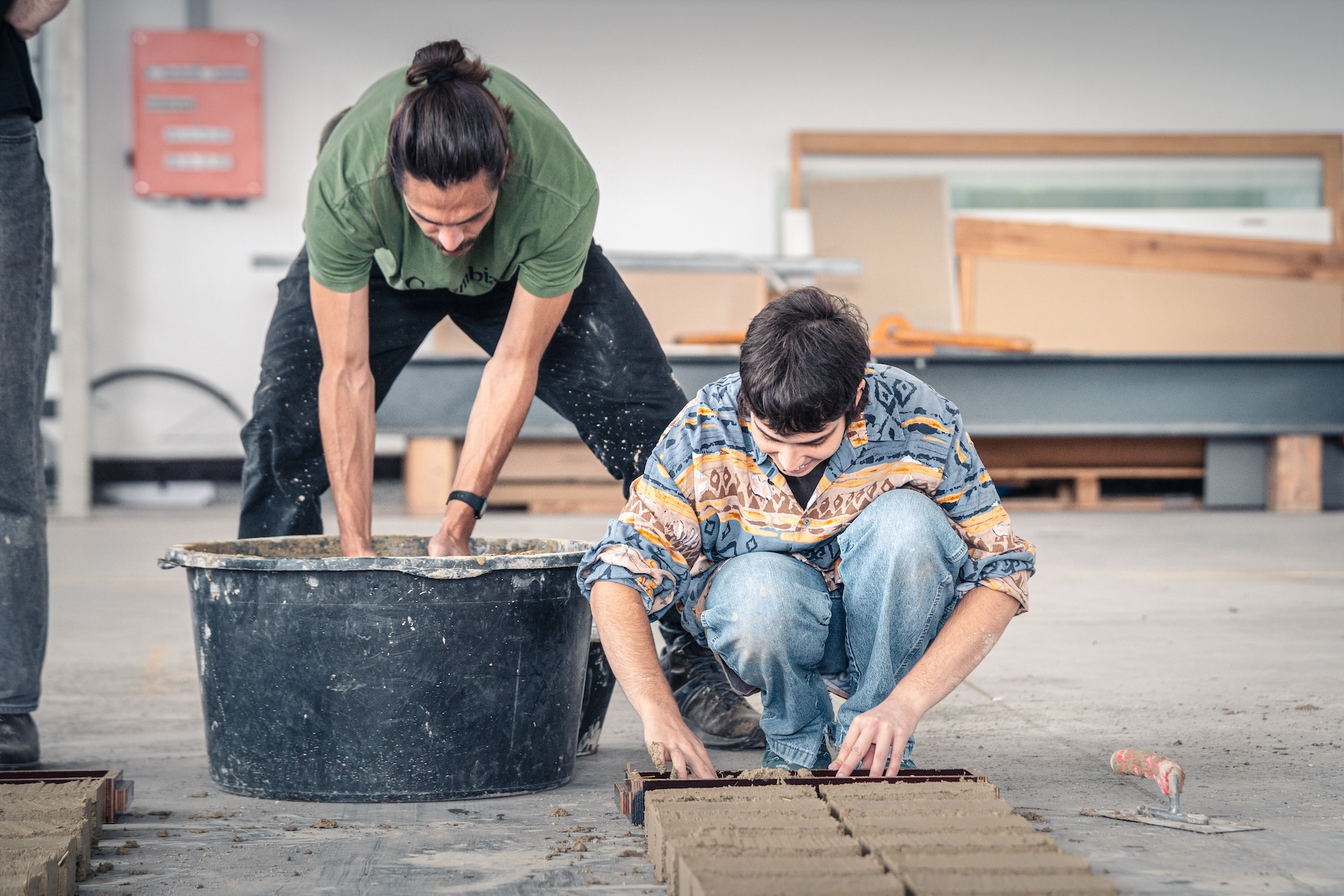 Teilnehmende des Lehmbau Workshops stellen Adobe-Ziegel von Hand her. 