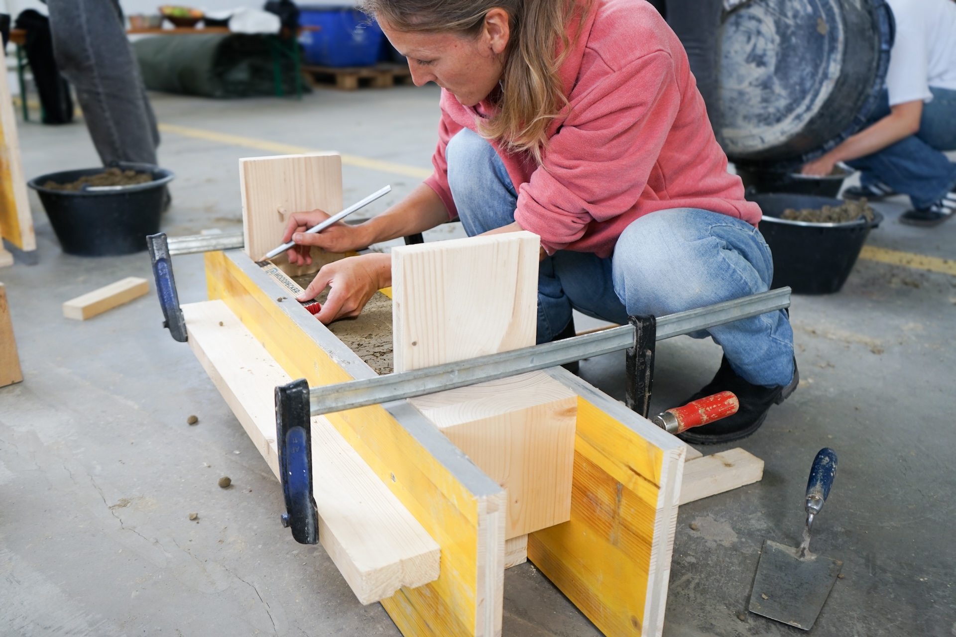 Teilnehmende bauen Holzschalungen und giessen darin Lehm.